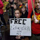 College students protesting, holding sign that reads "Free education for all"