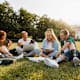 Friends sitting on grass outdoors in campus area.