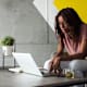 Black female college student working on her laptop in a simple and modern space.